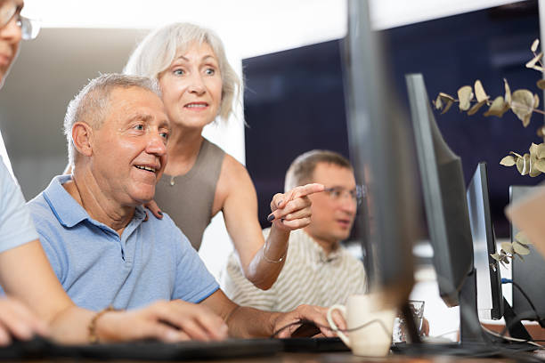 istock Elderly people help each other learn how to use computer. Positive woman suggests right decision to an mature man 2254446154