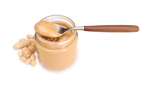 istock Tasty nut paste in jar, spoon and peanuts isolated on white 2254447678