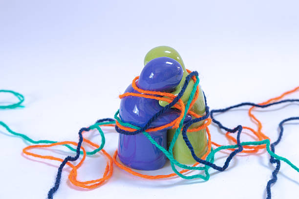 Two figurines hugging each other amidst a selection of multi-coloured strings