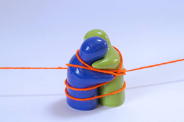 Blue and green figurines tied up in a red string hugging each other