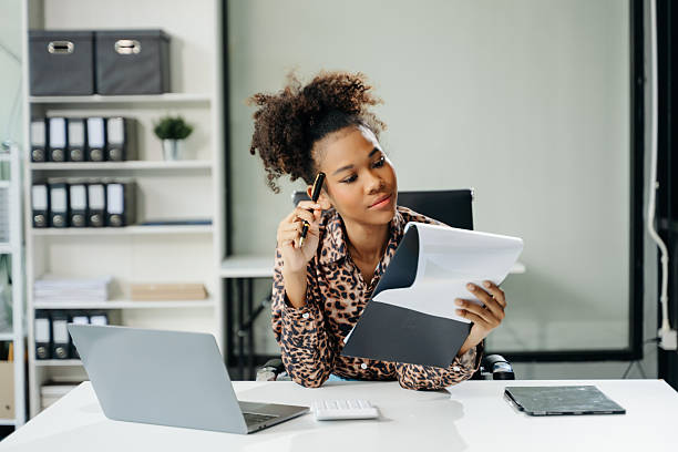 istock Young Asian businesswoman working with working notepad, tablet and laptop documents talking on the smartphone, tablet and laptop video call tax 2254449416