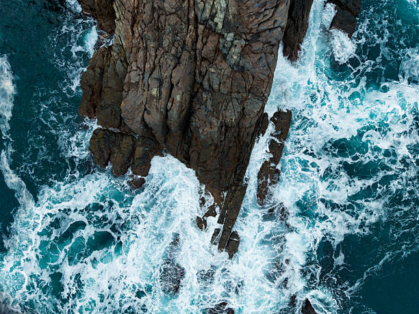 istock Waves crash against rugged cliffs under the bright sunlight of a clear day by the ocean 2254450801