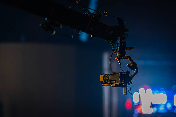 istock Camera mounted on a crane arm, capturing dynamic shots in a dimly lit studio, with colorful lights creating an engaging atmosphere for film production 2254451079
