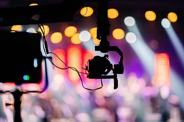 istock Camera equipment with gimbal stabilizer is positioned in front of a vibrant stage, capturing dynamic lighting and colorful bokeh effects during a live performance event 2254451174