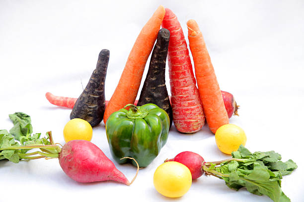 Fruit and vegetable themes: Close-up of carrot group with assorted organic tropical fruits and vegetables in a rustic kitchen background with natural window lighting. Bell Red Peppers, carrots, lettuce, tomatoes, onions, celery, broccoli, cucumber, zucchini, arugula, eggplant, papaya, bananas, pineapple, melon, corn.