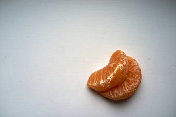 two mandarin segments resting on clean surface morning prep for recipe or snack, quiet minimalist mood, soft