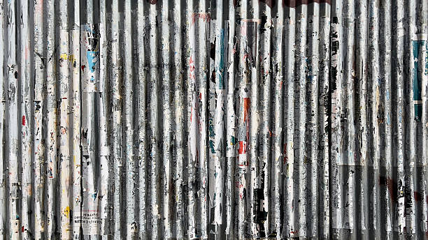 Corrugated metal wall with peeling urban posters and texture