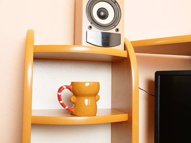 Ceramic mug on shelf near speaker and computer monitor