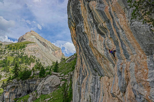 istock Focused climber ascends a layered rock face in a dramatic mountain landscape 2254457089
