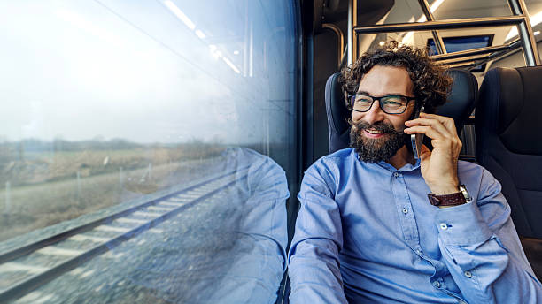 istock Smiling man talking on phone traveling on train 2254457652