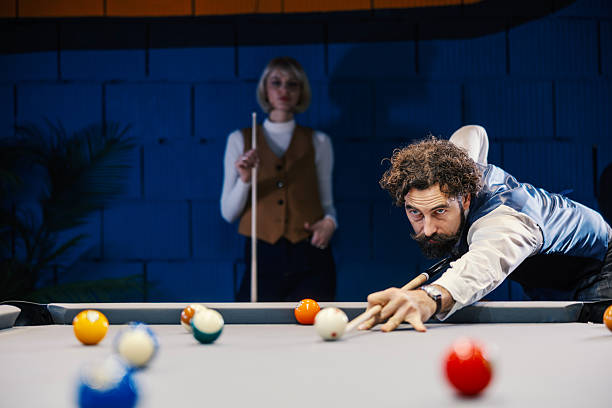 istock Man concentrating playing billiards while woman waits 2254458410