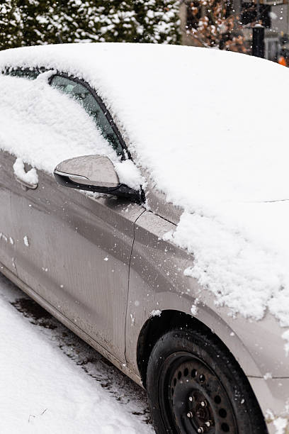 istock A parked car is covered with a thick layer of snow on a winter evening. Snowflakes fall gently, creating a wintry scene in an urban setting 2254464155