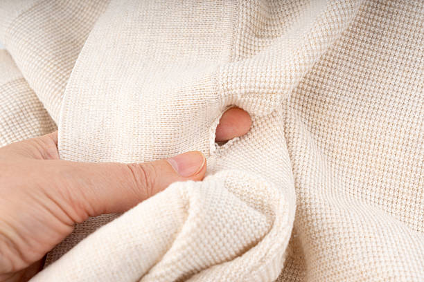 istock Torn fabric with a hole close-up. Damaged textiles background, old rip cotton material 2254467216