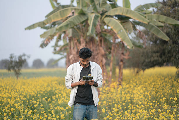 Indian man launching and controlling a drone in a mustard flower field. Represents modern agriculture, crop monitoring, and digital transformation in rural India. Suitable for technology, farming, sustainability, and innovation concepts.