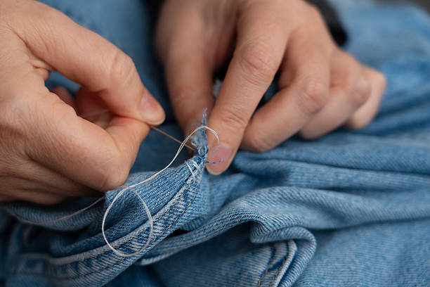 istock Woman mends jeans by hand with needle 2254468589
