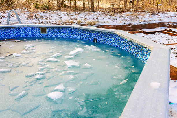 istock Frozen pool surrounded by trees snow during winter in quiet backyard setting 2254469237
