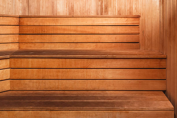 Wooden benches are set up in a sauna. The wood creates a warm and inviting space for relaxation.