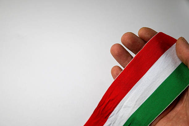 Close-up of a hand holding a red, white and green fabric ribbon inspired by the national colors of Hungary, with copy space on a white background. Suitable for advertising, design and promotional use.