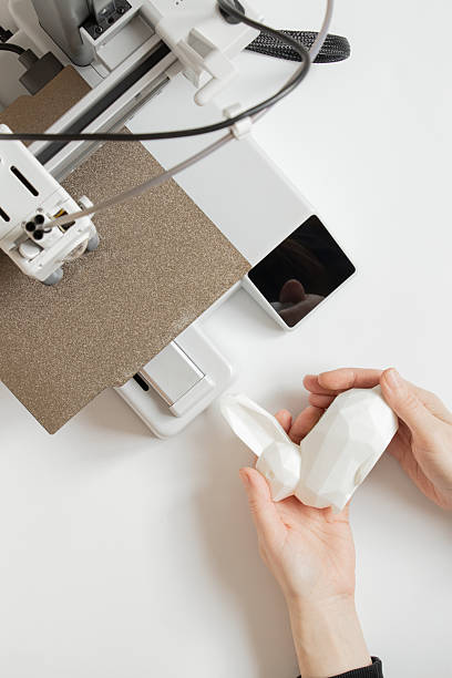 istock A desktop 3D printer and a white low-poly bunny on the printer, along with female hands, technologies for additive manufacturing 2254496652