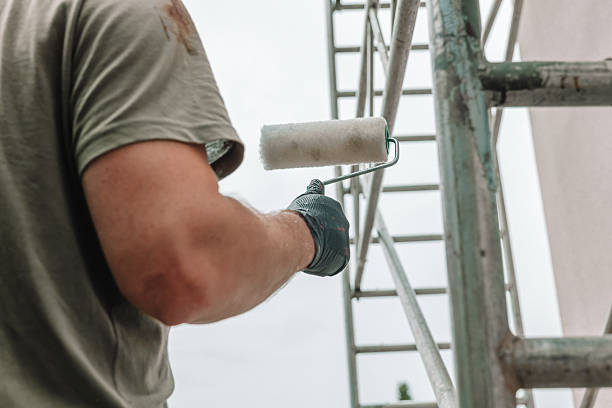 istock Close-up of a paint roller held by a worker during exterior building renovation. Construction scaffolding in background. Professional painting and maintenance work concept 2254498348