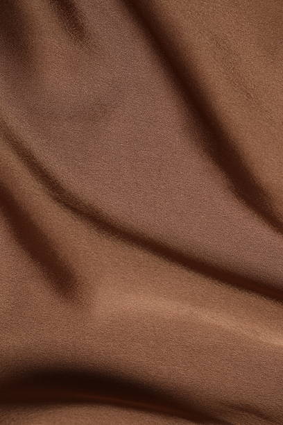 istock Brown silk satin. Shiny smooth fabric. Soft folds. Luxury background with space for design. Flat table, top view 2254502062