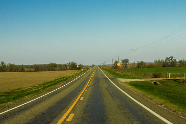 Series of photographs capturing quiet rural roads stretching through open countryside in Texas. Empty highways, gentle curves, power lines, trees, and wide skies create a sense of movement, distance, and solitude. The images convey themes of travel, journey, freedom, rural America, transportation, and calm landscapes, with strong leading lines and natural light. Ideal for concepts related to road trips, direction, progress, exploration, simplicity, and peaceful rural life.