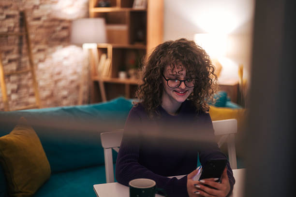istock Young woman smiling using smartphone at home 2254509951