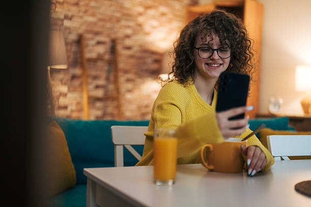 istock Young woman having breakfast and using smartphone 2254510821