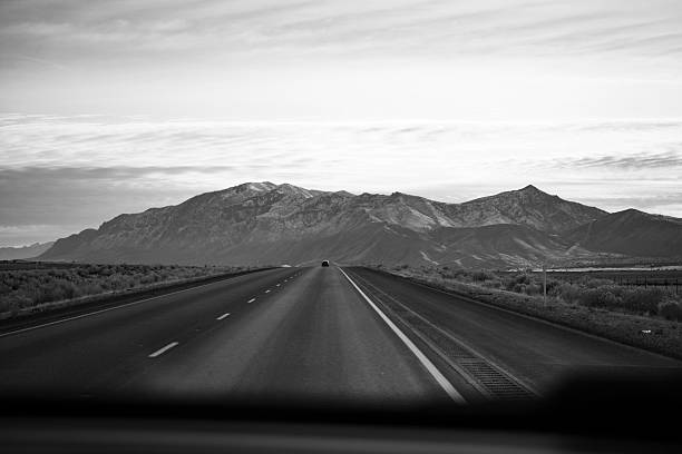 istock Black and White Road Trip Through Mountain Landscape With Camper 2254512834