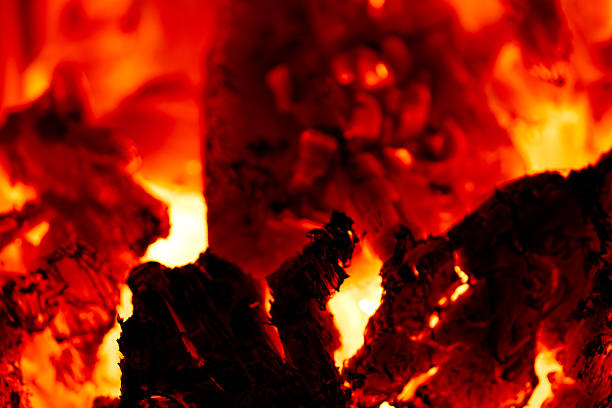 Burning wood transforming into red-hot glowing embers and charcoal, creating intense heat