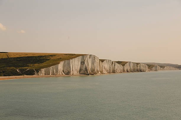 A breathtaking panoramic view of the iconic Seven Sisters chalk cliffs stretching along the English coastline under a bright sky. This majestic landscape highlights the natural beauty and dramatic cliffs, perfect for travel, nature, and environmental projects. Ideal for use in tourism promotions, educational materials, and scenic backgrounds.
