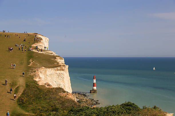 View of chalk cliffs, the lighthouse and the English Channel coastline against a stormy sky