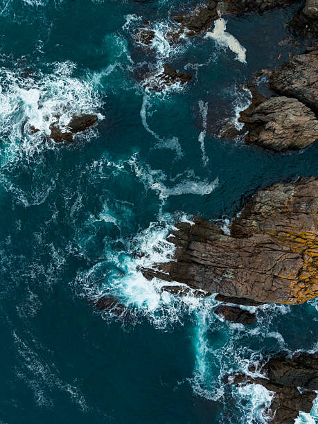 istock Waves crash against rugged cliffs under a bright blue sky at the shoreline, creating a stunning seascape in the early afternoon light 2254517391