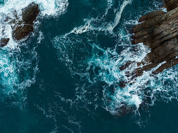 istock Waves crashing against rugged rocks at a tranquil coastal scene during midday, capturing nature's beauty and power in vivid detail 2254517602