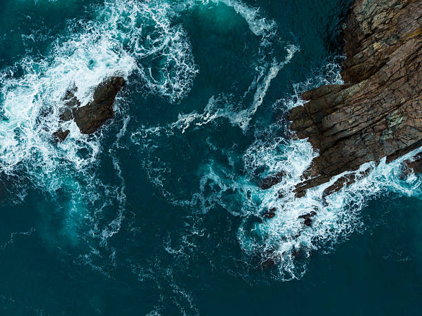 istock Waves crashing against rugged rocks in a serene coastal landscape during a sunny afternoon, showcasing nature's power and beauty 2254517708