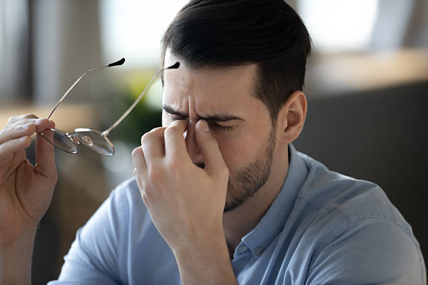 istock Closeup tired millennial man taking off eyewear massaging nose bridge 2254520479