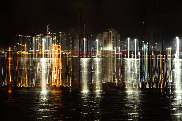 City lights creating abstract vertical lines reflecting on the dark water at night