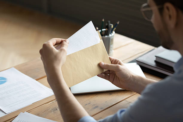 istock Closeup young businessman holding envelop with paper letter in hands 2254520587