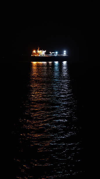 istock Ship illuminating dark ocean water at night with colorful lights 2254520640