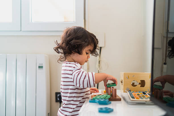 istock Child actively engaged with a wooden educational toy, exploring shapes, colors, and problem-solving skills indoors 2254520979