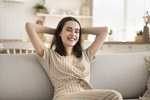 istock Woman put hands behind head resting leaned on cozy sofa 2254522009
