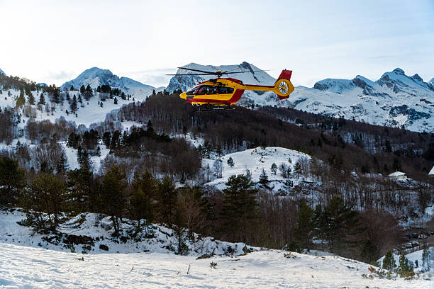 A small orange helicopter against the backdrop of the snow-capped Alps in Austria