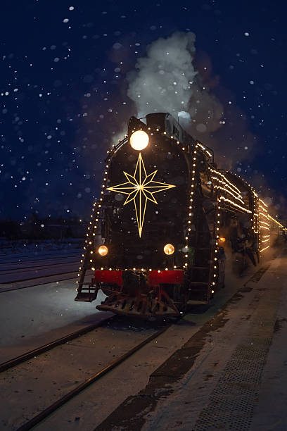 istock festively decorated with lights retro Christmas train on rails, snowy evening 2254525078
