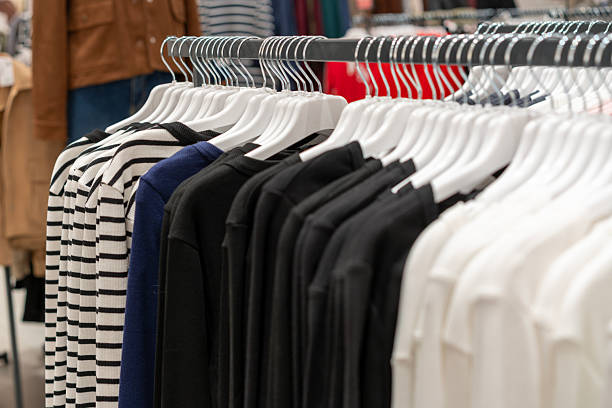 A selection of casual clothing neatly arranged on hangers inside a modern retail store. Image represents minimalist fashion, apparel retail, everyday clothing, and contemporary shopping environment. Suitable for concepts related to fashion retail, seasonal collections, consumer lifestyle, and in-store merchandising.