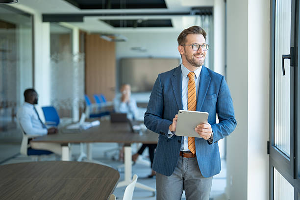 istock Businessman smiling and holding digital tablet in modern office 2254531858