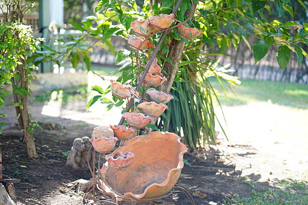 A charming garden water feature showcases colorful decorative shells while surrounded by lush greenery. Sunlight beautifully enhances the serene atmosphere of this backyard setting.