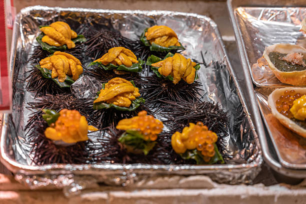 Fresh, vibrant sea urchin (uni) and salmon roe (ikura) delicacies meticulously presented on ice in a bustling Japanese seafood market. A gourmet treat for connoisseurs of Asian cuisine.