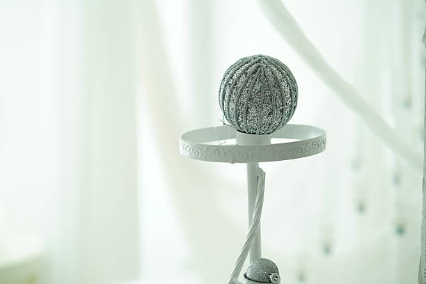 Decorative Table Arrangement with Shimmering Silver Sphere on White Plate in Soft Natural Light Creating an Elegant Ambiance for Festive Occasions