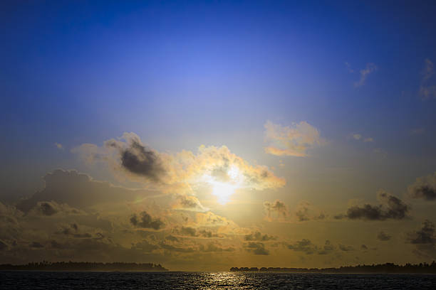 A serene sunset over calm ocean with scattered clouds and vibrant sky, creating peaceful and tranquil atmosphere