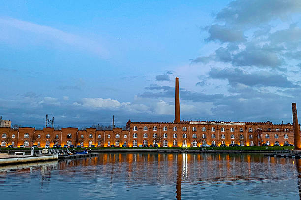 istock Former industrial building reflected in water at twilight 2254554863